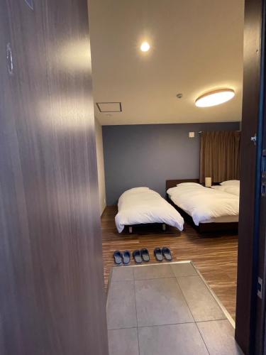 two beds in a room with shoes on the floor at Guest House Goettingen in Kyoto