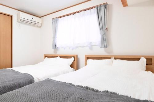 zwei Betten in einem Schlafzimmer mit Fenster in der Unterkunft OSAKA COZY HOUSE For Family & Group 2bedroom in Takaishi