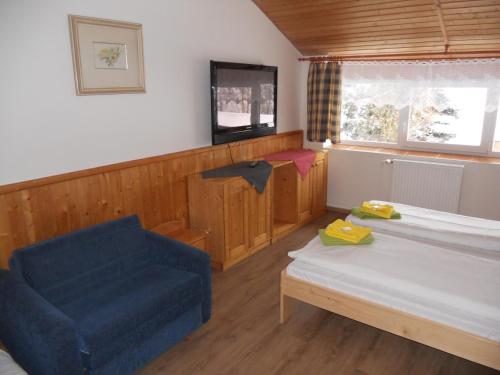 a room with a bed and a chair and a couch at Penzion Kamzík in Česká Kamenice