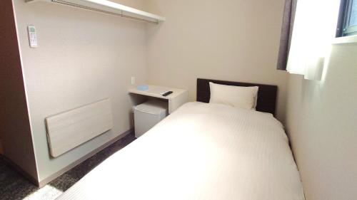 a small room with a bed and a night stand at Ｓｗｉｍｍｙ Ｉｎｎ Ｏｎａｇａｗａ - Vacation STAY 44059v in Onagawa
