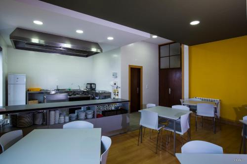 a kitchen with tables and white chairs in a room at Hostel EntryFik in Maçeira