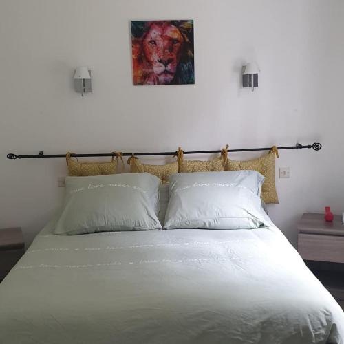 - une chambre dotée d'un lit blanc avec une photo sur le mur dans l'établissement La heckeliere, à La Houssière