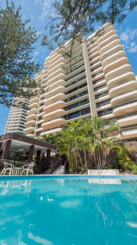 a hotel with a swimming pool in front of a building at Norfolk Luxury Beachfront Apartments Gold Coast in Gold Coast