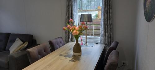 a dining room table with a vase of flowers on it at Blissful in Hoenderloo