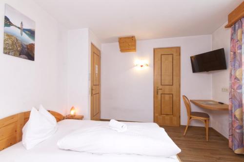 a bedroom with a bed and a desk and a television at Pension & Residence Astoria in Prato allo Stelvio