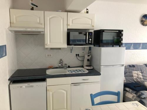 Elle comprend une petite cuisine avec des placards blancs et un réfrigérateur blanc. dans l'établissement Le Triskel - Studio à 50 mètres de la plage, à Fort-Mahon-Plage