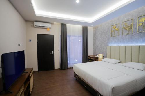 a bedroom with a bed and a flat screen tv at d' Omah Afi 1 in Jarakan