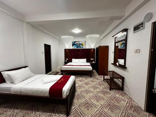 a hotel room with two beds and a mirror at Serenity Lake Nuwara Eliya in Nuwara Eliya