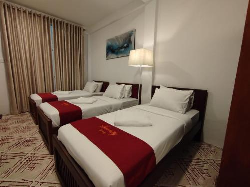 a hotel room with three beds in a room at Serenity Lake Nuwara Eliya in Nuwara Eliya