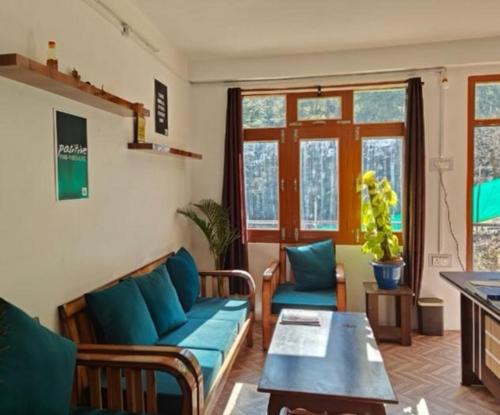 a living room with a blue couch and a table at Crest of Bliss in Kūfrī