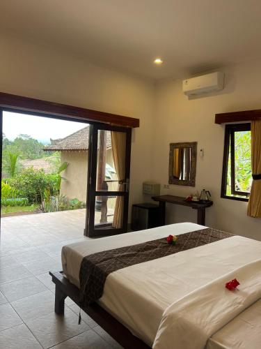 a bedroom with a large bed and a large window at Giri Carik in Sidemen