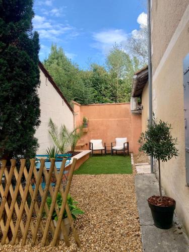 a small garden with two chairs and a fence at La petite maison in Neuvic