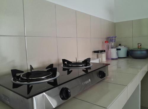 a kitchen with a stove with two frying pans on it at Zayyan Homestay Parit Buntar in Parit Buntar