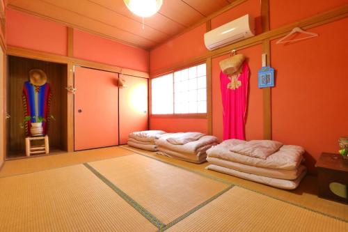 a room with four beds in a room with orange walls at Hoshinosora in Shodoshima