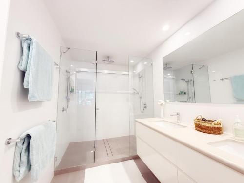 une salle de bain blanche avec une douche et un lavabo dans l'établissement Reef Luxury Apartment, à Port Douglas