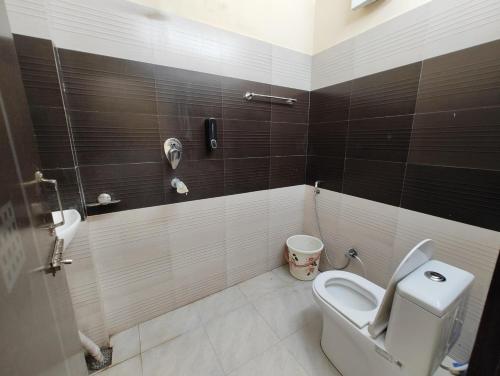 a bathroom with a toilet and a phone on the wall at Shreya's Homestay, Your Sacred Nest in Ujjain