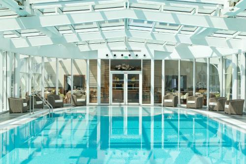 a pool in a hotel with chairs and a ceiling at Miramar La Cigale Hotel Thalasso & Spa in Arzon