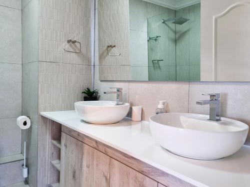 Un baño con dos lavabos y un espejo. en 'Goldwater on Beach' - 3 Bedroom Beachfront with Balcony & BBQ - Sleeps 6, en Gordonʼs Bay