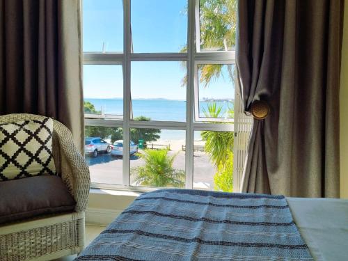 Un dormitorio con una ventana con vista al mar. en 'Goldwater on Beach' - 3 Bedroom Beachfront with Balcony & BBQ - Sleeps 6, en Gordonʼs Bay