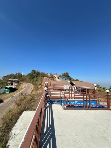 a wooden bridge over a road next to the ocean at The Moon House บ้านพักภูทับเบิก Phu Thap Buek in Ban Maeo Thap Boek