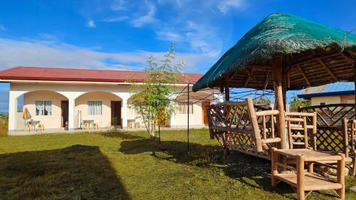 een huis met een grasparasol en stoelen in de tuin bij Mangoverde Guesthouse in Moalboal