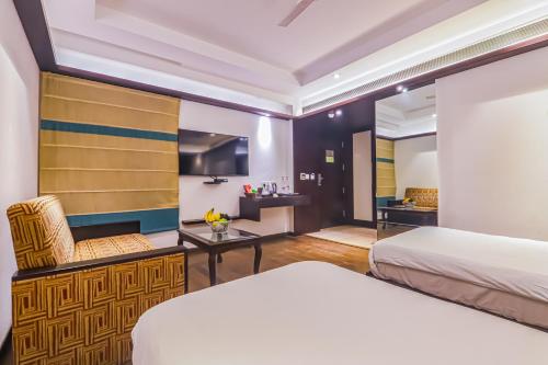a hotel room with two beds and a chair at Hotel Godwin Deluxe - Free Airport Pick-Up in New Delhi