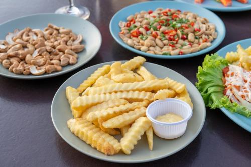 a table with plates of food with french fries and dip at One Sakon Nakhon Hotel in Ban Na Weng