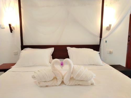 two swans made out of towels on a bed at White Villa - Homestay in Tangalle