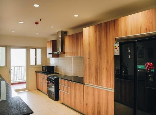 a kitchen with wooden cabinets and a black appliances at Elles Residence - Serenity in Dar es Salaam