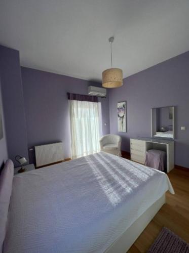 a bedroom with a white bed and a blue wall at Villa Tranquility in Skála Oropoú