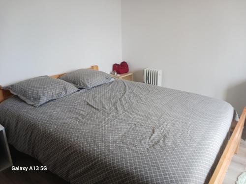 - un lit avec une couette grise et 2 oreillers dans l'établissement Maison a etage, au Le Verdon-sur-Mer