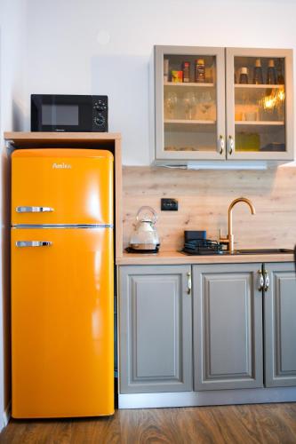 an orange refrigerator in a kitchen with a sink at Tweet Apartments with Sauna and optional Breakfast Close To Terme Sveti Martin in Štrigova