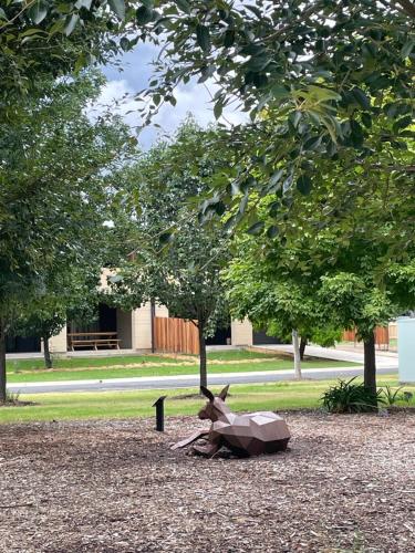 a statue of a deer laying on the ground under a tree at Riverbank House in Mudgee