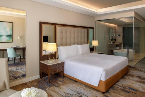 a bedroom with a large bed and a bathroom at Dusit Doha Hotel in Doha