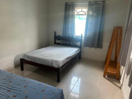 a bedroom with a bed and a window with blue curtains at casa de praia pontal do Piraquiaçu in Aracruz