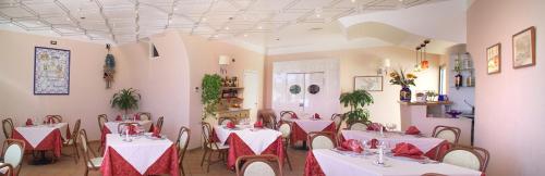un restaurante con mesas blancas y sillas con servilletas rojas en Hotel Paladini di Francia en Lampedusa