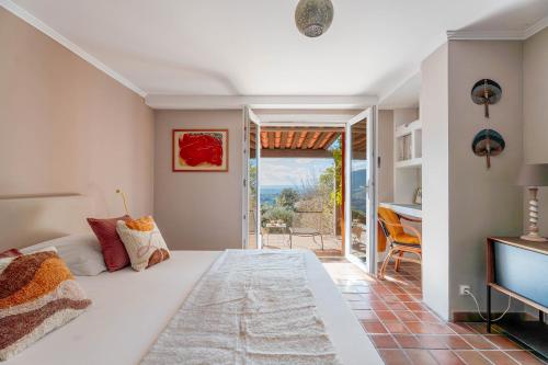 - une chambre avec un grand lit blanc et une porte coulissante en verre dans l'établissement Villa 10p Vue Mer Grande Piscine et Dépendance, à La Londe-les-Maures