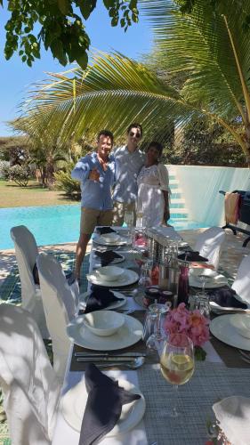 a group of three men standing around a table with plates at Dhow House in Shela