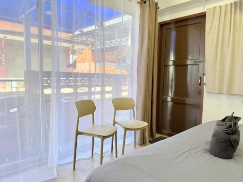 a cat laying on a bed next to two chairs at เทพกุญชร Budget-Friendly Room in Ban Lam Rua Taek