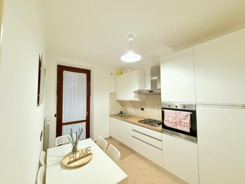 a white kitchen with a table and a refrigerator at LA Home - Animal House in Viareggio