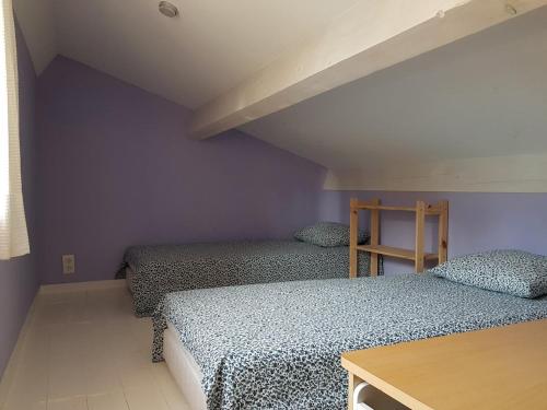 deux lits dans une chambre aux murs violets dans l'établissement Maison familiale sur la route du Ventoux, à Mormoiron