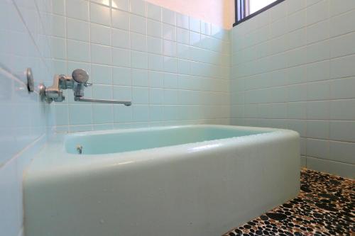 a bath tub in a bathroom with white tiles at Hoshinosora in Shodoshima