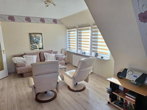 a living room with white chairs and a couch at Villa Duli in Bad Harzburg