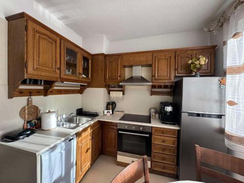 Una cocina con gabinetes de madera y electrodomésticos de acero inoxidable. en Апартамент Слънчев дом, en Smolyan