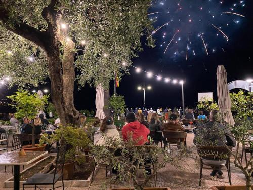 a group of people sitting at tables under a tree with fireworks at Albergo Bellavista in Limone sul Garda