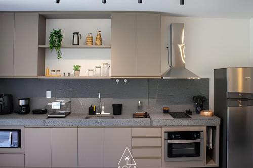 a kitchen with white cabinets and stainless steel appliances at Villa Naluri - Seu Refúgio a 50 metros da praia em Japaratinga in Japaratinga