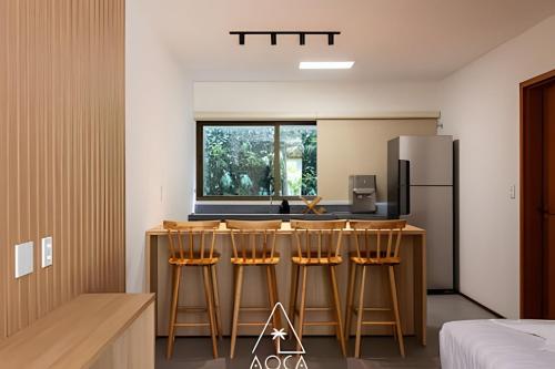 a kitchen with a bar with chairs and a refrigerator at Villa Naluri - Seu Refúgio a 50 metros da praia em Japaratinga in Japaratinga