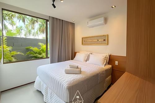 a bedroom with a bed and a large window at Villa Naluri - Seu Refúgio a 50 metros da praia em Japaratinga in Japaratinga