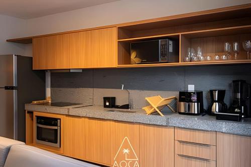 a kitchen with wooden cabinets and a counter top at Villa Naluri - Seu Refúgio a 50 metros da praia em Japaratinga in Japaratinga