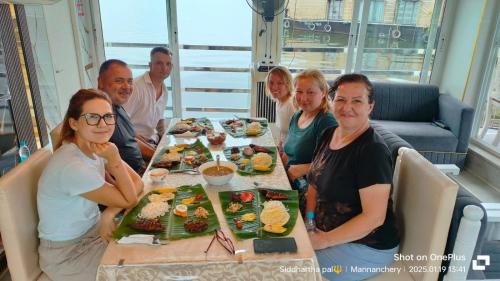 a group of people sitting around a table with food at Beach Paradise Day Cruise Houseboat in Alleppey
